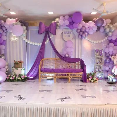 A full view of our chic 'Baby 2.0' bow-themed stage. The setup features a large purple bow, elegant draping, a custom floor with bow decals, and a beautiful balloon arch.