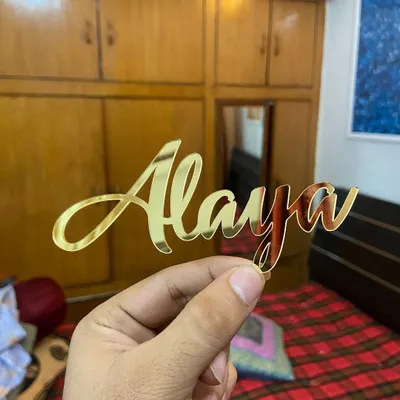A classic and elegant "Alaya" name topper in a beautiful gold script. This simple design adds a personalized touch without overwhelming the cake.