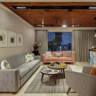 The living room at Rue 32 exudes comfort and style. We created an inviting enclave with a linear grey sofa, a rose pink loveseat, and a lounge chair in checks. The wooden ceiling adds warmth and unites the entire space.