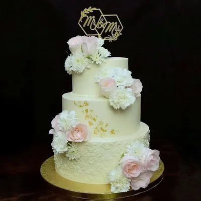 There is something timeless about a three-tier wedding cake. This one features delicate stenciled buttercream, fresh pink and white roses, and a custom "Mr & Mrs" topper, making it a classic and romantic choice for a wedding.