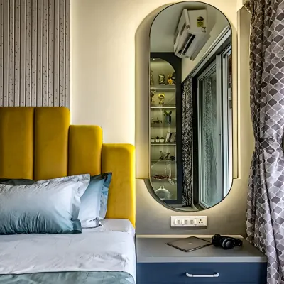 This bedroom features a vibrant yellow upholstered headboard that adds a pop of color. An elegant, full-length mirror with backlighting doubles as a design feature and enhances the room's brightness.