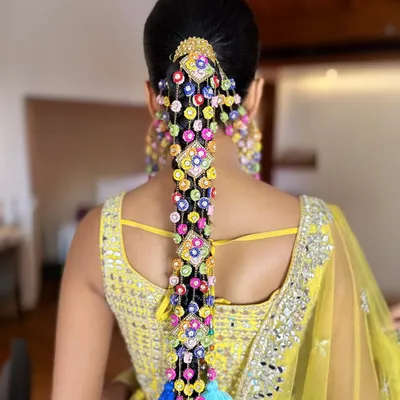 A back view of the spectacular Haldi braid created for Aish. The intricate arrangement of the colorful accessories and tassels creates a waterfall of color that is absolutely breathtaking.