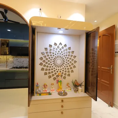 A minimalist and modern mandir design. This compact unit features a beautiful back-lit jali panel and drawers for storage, fitting perfectly in a small nook.