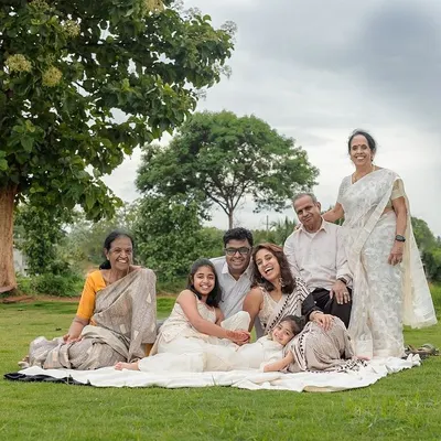 A beautiful portrait of a multi-generational family enjoying a picnic-style shoot outdoors. We find a comfortable spot under a tree where everyone, from grandparents to grandchildren, can relax and be together.
