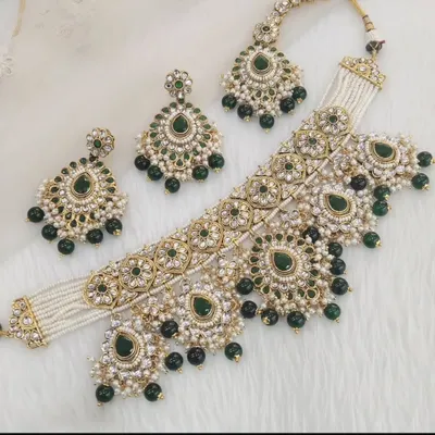 A beautiful Kundan choker set with green stones and pearl drops, complete with matching earrings and a maang tikka.