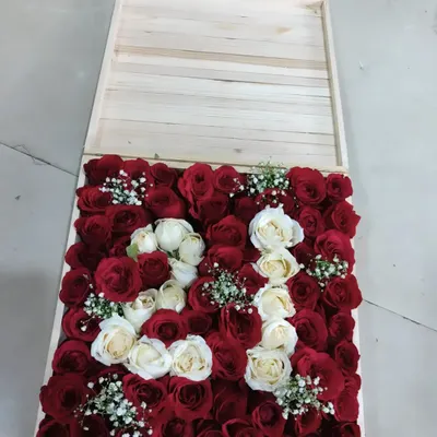 A close-up look at one of our custom initial hampers. This one, featuring the letter 'R', uses a combination of deep red and soft white roses, accented with delicate baby's breath. The arrangement is set inside a light-colored wooden box, which can be kept as a keepsake long after the occasion.