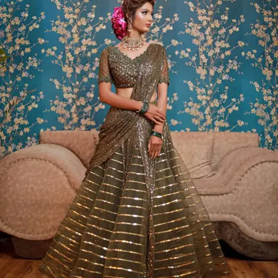 A stunning olive green striped sequin lehenga saree. This modern, pre-draped outfit is perfect for a wedding guest who wants an elegant, hassle-free, and glamorous look.