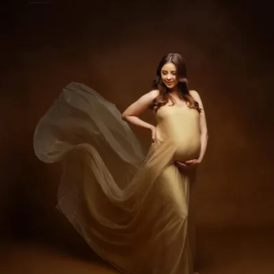 A classic maternity pose in a flowing golden gown. We use fabric tossing to create a sense of movement and drama, making you look and feel like a goddess.