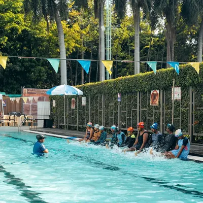 A group of young swimmers learning kicking techniques by the poolside. We use these drills to build leg strength and coordination.