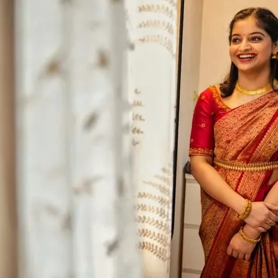 A candid, happy moment from her ring ceremony. This subtle makeover in a classic red Kanjivaram saree highlights her natural beauty with a simple hairstyle and minimal jewelry.