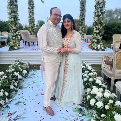 A valued client at an outdoor wedding, wearing a bespoke Nehru jacket in a light, subtly patterned fabric over a silk kurta. This piece was crafted to radiate elegance and sophistication.