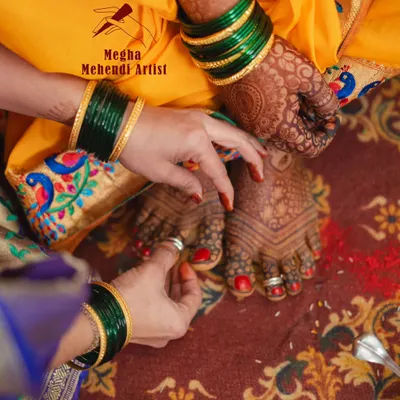 A candid shot from a wedding ceremony, showing the bride's beautifully adorned feet. The design is traditional, with simple lines and a focus on the rich henna stain.