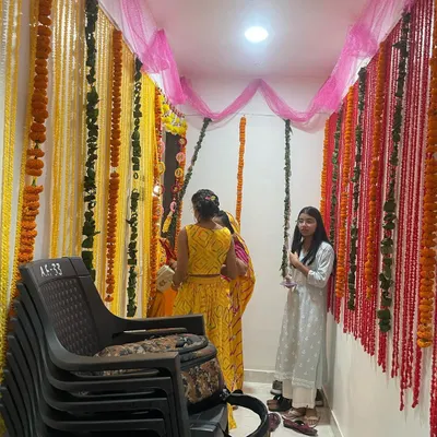 A beautiful entrance decoration for a Griha Pravesh using strings of fresh yellow and red marigold flowers and pink chunni fabric. This creates a traditional and welcoming feel.