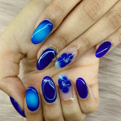 For our clients who love a pop of color, this design is a dream. We used a vibrant royal blue, creating a mix of cat-eye effect, ombré, and solid color nails. The highlight is the accent nails with hand-painted 3D flowers on a clear base, showing our attention to artistic detail.