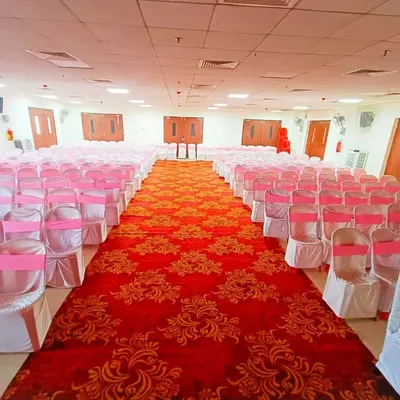 Beyond just backdrops, I also handle large-scale event logistics like seating arrangements. For this event, I set up a large hall with neatly arranged chairs covered in white and pink, with a grand red carpet aisle, ensuring the venue was ready for hundreds of guests.