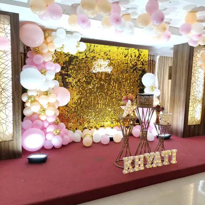 A stunning gold sequin wall creates a glamorous backdrop for this birthday party, perfectly complemented by a pink and white balloon garland and marquee letters.