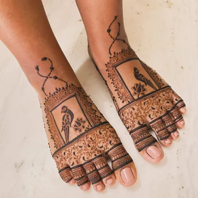 Foot mehndi can be so elegant. This engagement design features a unique parrot motif set within a decorative frame, with delicate chain details extending up the ankle for a beautiful, complete look.