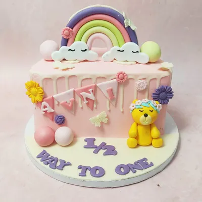 We celebrate the halfway mark to a big milestone with this adorable "halfway to one" cake. A sleepy teddy bear, a pastel rainbow, and a sweet banner adorn this pink drip cake, making it a perfect way to mark six months.
