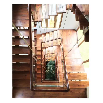 The signature view of the 'Aangan' house staircase, a spiral of locally sourced timber and steel. The design creates a visual vortex, connecting the home's levels while celebrating natural materials.