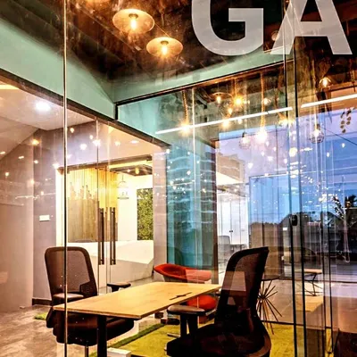 We designed this corporate office in Bangalore with glass partitions and modern pendant lighting to create an open, collaborative atmosphere. The design encourages transparency while defining functional zones like this meeting cabin.