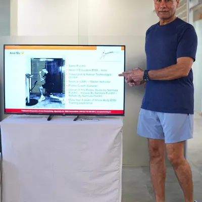 I use real case studies and visual aids to explain how to structure an EMS session. Here, I am pointing out the key components of a client's initial assessment and program design on screen.