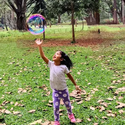 What do you see in the bubble? A moment of pure, simple magic as a child reaches for a giant, shimmering bubble in the park.