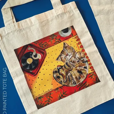 I can turn a simple canvas tote into your new favorite bag. This custom painting features a tabby cat sleeping in a warm, cozy room, making it a perfect example of wearable art for everyday use.