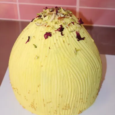 Celebrating Ganesh Chaturthi with our creative modak-shaped cake. This one is covered in yellow frosting with a textured finish and topped with pistachios and rose petals.