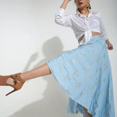 Capturing "moving static" in the studio. This shot freezes a moment of dynamic movement, with the flowing blue skirt and high kick creating an energetic and stylish image against a clean white background.