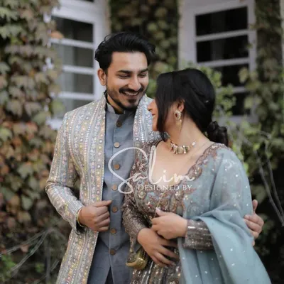 A beautiful shot of a couple enjoying a moment together. I designed the groom's elegant grey-blue Indo-Western outfit, featuring a patterned jacket that complements his partner's attire perfectly.