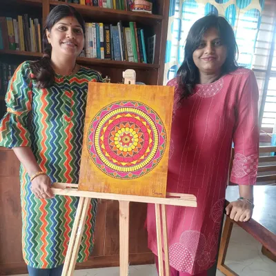 Bhavana with her beautifully completed mandala, painted on a textured background. The warm colors and intricate patterns make this a stunning piece of decor.