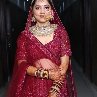 A happy client looking gorgeous in her magenta lehenga and a sparkling Polki choker set for her special event.