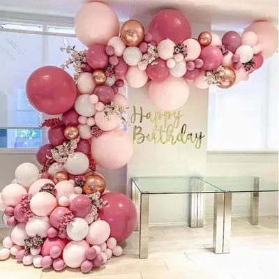 This large, organic balloon arch was customized for a birthday celebration. It features a mix of pink, rose gold, and white balloons in various sizes, creating a stunning frame for a dessert table or photo corner.