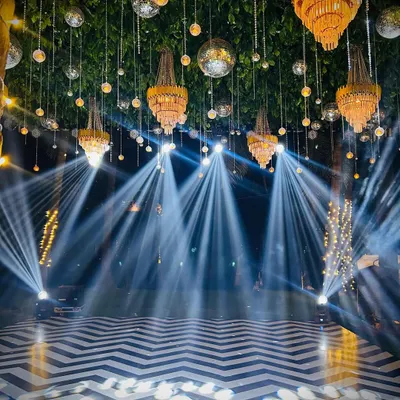 This is how we set the stage for an epic Sangeet night. A chevron dance floor, a ceiling of hanging greenery, disco balls, and dramatic spotlights create an electric atmosphere that invites everyone to the party.