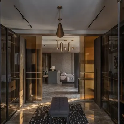 The walk-in closet leading to the master bathroom in the Aikaa villa. We used smoked glass and dark wood to create a moody, luxurious transition, with the bathroom visible beyond.