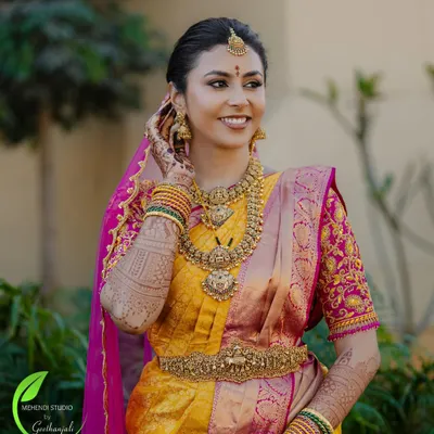 A radiant bride on her wedding day, her beautiful smile complemented by the rich color of her bridal mehendi.