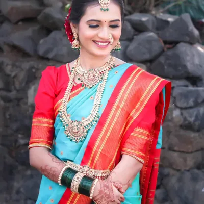 A classic bridal portrait featuring a beautiful bride in a traditional sky-blue and red Paithani saree. The focus is on her serene expression and the rich details of her attire.