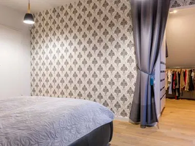 This bedroom project shows a curtain used as a closet door. The dark grey fabric provides a soft yet effective visual separation, hiding the clothing rack from view. This is a fantastic way to manage storage in a bedroom or studio apartment where you need a flexible and non-permanent dividing solution.