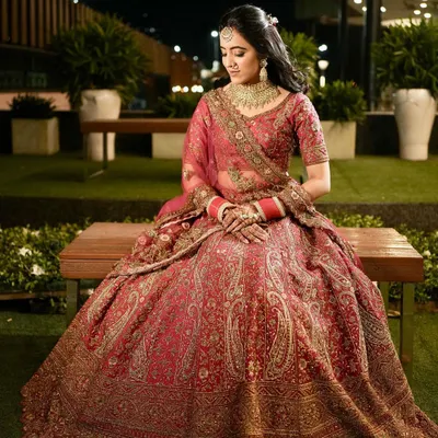 A stunning full-length portrait of the bride in her intricately detailed red lehenga. This shot, taken before the ceremony, captures her elegance and the magnificent craftsmanship of her attire.