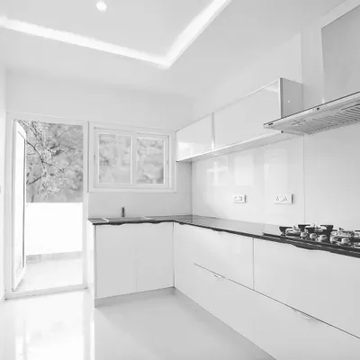A completed modern kitchen featuring a clean, all-white design with handleless cabinetry for a seamless look. The layout is optimized for easy movement, with a black granite countertop providing a durable and contrasting workspace.