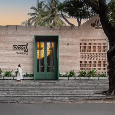 The facade of Ishtaa at dusk. The warm interior light glows through the green-framed doorway and brick lattice, creating a welcoming and intriguing street presence for the restaurant.