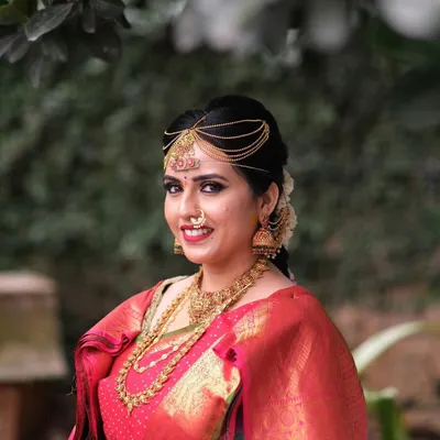A radiant portrait of my bride Chinmayi. Her makeup features a classic red lip and defined eyes, perfectly complementing her red Kanjeevaram saree and gold temple jewellery.