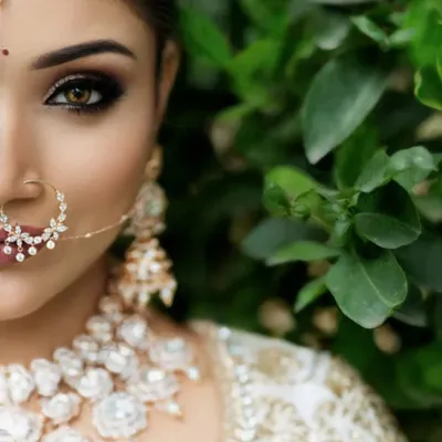 An intense and beautiful close-up of a bride, focusing on her stunning eye makeup and intricate nose ring.