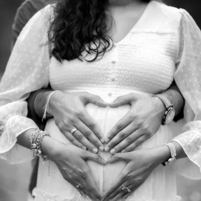 A close-up black and white shot of the parents' hands forming a heart on the baby bump. This iconic pose becomes even more powerful in monochrome, focusing solely on the symbol of love.