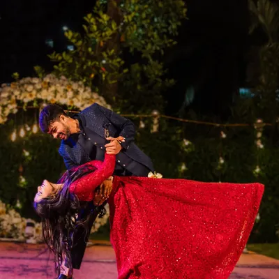 The couple shares a romantic dance, with the groom dipping the bride in her stunning red gown. This is a perfect, movie-like moment from their reception.