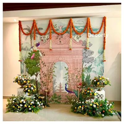 A stunning Pichwai art backdrop for a Mundan ceremony. The traditional Indian artwork is complemented by marigold garlands and lush floral arrangements, creating a beautiful blend of art and nature.