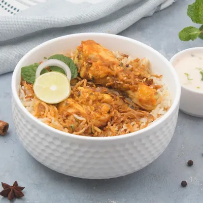 A classic bowl of our chicken dum biryani, made with fragrant long-grain rice and tender chicken pieces. We serve it with a side of cooling raita to balance the authentic spices.