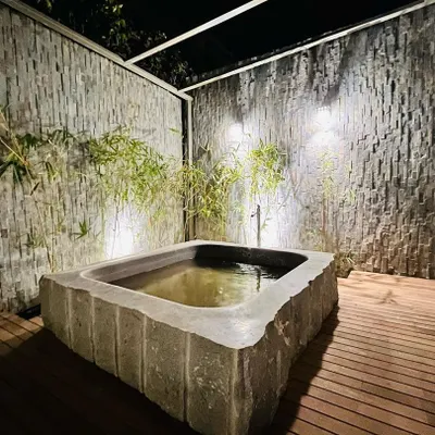 We specialize in creating serene, Zen-inspired spaces. This custom-built Japanese stone bath, set against textured stone walls and bamboo, provides a private, tranquil retreat. We manage all aspects, from sourcing the natural stone to the plumbing and lighting installation.