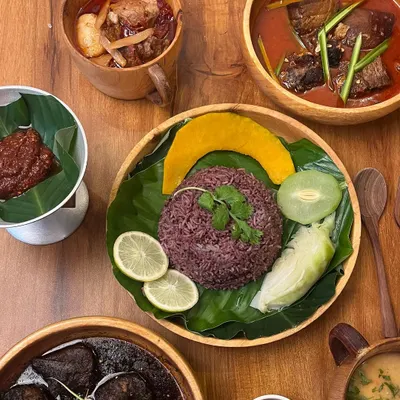 A top-down view of our Naga thali, showcasing the variety of dishes included. You can see the red sticky rice, smoked pork, boiled vegetables, and different chutneys, offering a complete culinary journey.