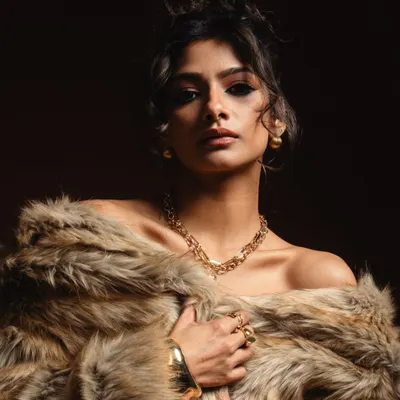 A powerful editorial shot featuring a bold, winged smokey eye. The combination of the intense makeup, messy updo, and luxurious fur coat creates a high-fashion statement.